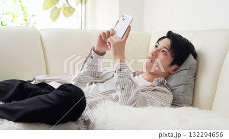 寝ながらスマホを見るアジア人男性 寝ながらスマホを見るアジア人男性 132294656