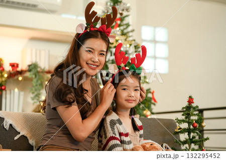 Christmas Celebration. Mother and daughter enjoying festive moments with reindeer antlers. Christmas Celebration. Mother and daughter enjoying festive moments with reindeer antlers. 132295452