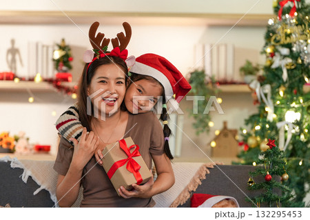 Festive Family Bonding. Mother and daughter sharing a Christmas gift with joy. 132295453