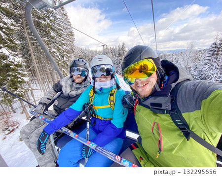 Friends Enjoying Ski Lift in Snowy Mountains 132295656