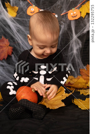 Baby in Skeleton Costume with Pumpkin and Leaves Baby in Skeleton Costume with Pumpkin and Leaves 132295755