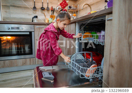 Little helper organizes dishes in the kitchen while enjoying a cozy family moment during the evening Little helper organizes dishes in the kitchen while enjoying a cozy family moment during the evening 132296089