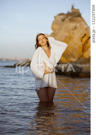 Young woman in summer white dress holds big shell in her hands 132297806