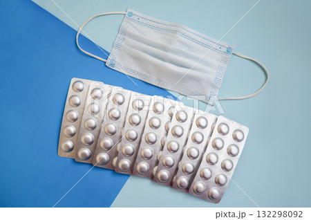 tablets in silver blisters and a medical mask on a blue background 132298092