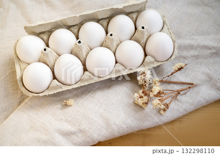 white eggs in a cardboard box, 10 pieces, on a surface made of natural materials. white eggs in a cardboard box, 10 pieces, on a surface made of natural materials. 132298110