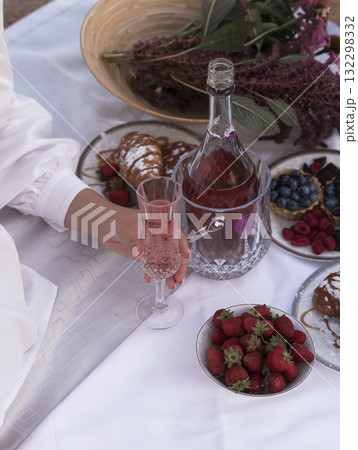Beautiful picnic with rose wine, strawberries and berries. Female hand holding glass with rose wine 132298332