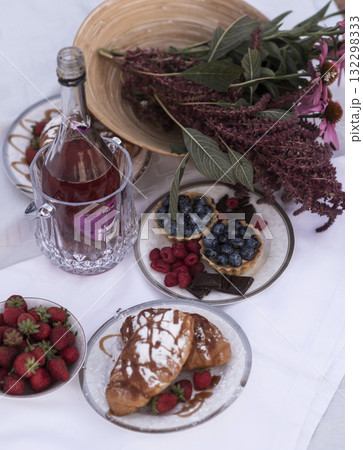 Beautiful picnic with rose wine, strawberries and berries. A cake with fruit on top of a table 132298333