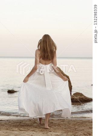 young girl in long white dress posing on the beach 132298339