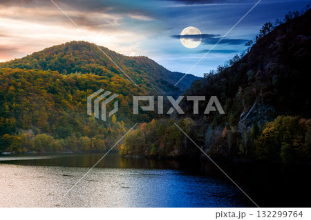 mountainous landscape with lake on autumn equinox. day and night time change concept. forest on hills near the shore of river under sky with moon at twilight. beautiful view of stunning place mountainous landscape with lake on autumn equinox. day and night time change concept. forest on hills near the shore of river under sky with moon at twilight. beautiful view of stunning place 132299764