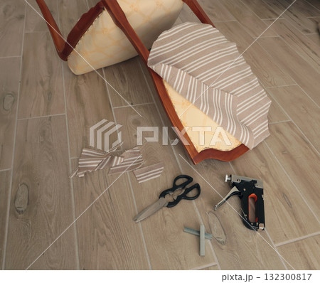 Restore old vintage chair in home. Fabric replacement. Antique furniture and modern striped linen and cotton fabric. Hobbies, crafts, and retro-minimalist style. Restore old vintage chair in home. Fabric replacement. Antique furniture and modern striped linen and cotton fabric. Hobbies, crafts, and retro-minimalist style. 132300817