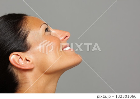 A woman is smiling and gazing upwards showcasing a sense of optimism and joy 132301066