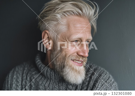 Man with silver hair and beard smiles while wearing a cozy sweater in a relaxed indoor setting Man with silver hair and beard smiles while wearing a cozy sweater in a relaxed indoor setting 132301080