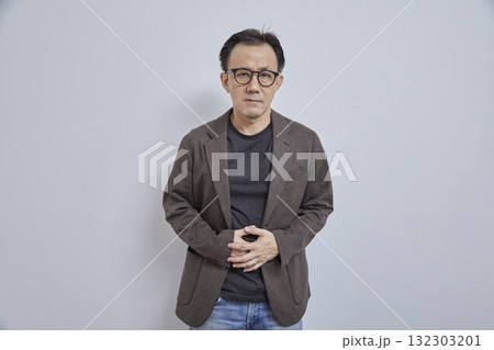 Asian businessman in suit suffers from stomachache on grey background. 132303201