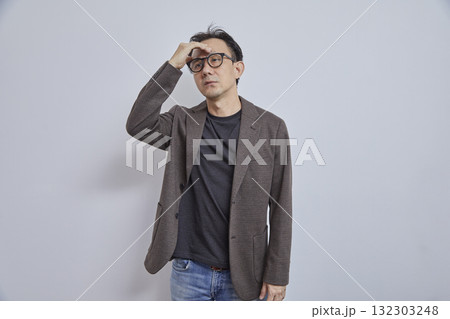 Portrait of stressed Japanese businessman in suit having headache on grey background. Portrait of stressed Japanese businessman in suit having headache on grey background. 132303248