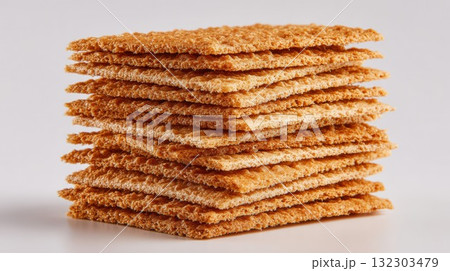 Stack of crispy golden crackers arranged in neat layers on white background, displaying texture and delicious baked snack food detail Stack of crispy golden crackers arranged in neat layers on white background, displaying texture and delicious baked snack food detail 132303479