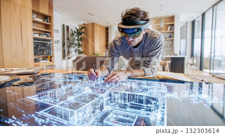 Architect using augmented reality headset to design and interact with holographic building model on desk in modern home office Architect using augmented reality headset to design and interact with holographic building model on desk in modern home office 132303614