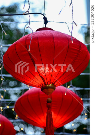 Close-up of the traditional Chinese red lantern with outdoor starry solar string lights. Big red lantern. Festive decoration. Mid-autumn festival, Chinese New Year decoration for celebration. Close-up of the traditional Chinese red lantern with outdoor starry solar string lights. Big red lantern. Festive decoration. Mid-autumn festival, Chinese New Year decoration for celebration. 132304026