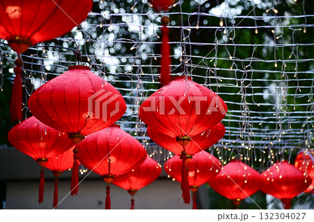 Close-up of the traditional Chinese red lantern with outdoor starry solar string lights. Big red lantern. Festive decoration. Mid-autumn festival, Chinese New Year decoration for celebration. Close-up of the traditional Chinese red lantern with outdoor starry solar string lights. Big red lantern. Festive decoration. Mid-autumn festival, Chinese New Year decoration for celebration. 132304027