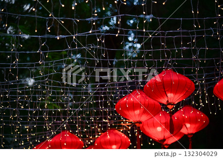 Close-up of the traditional Chinese red lantern with outdoor starry solar string lights. Big red lantern. Festive decoration. Mid-autumn festival, Chinese New Year decoration for celebration. Close-up of the traditional Chinese red lantern with outdoor starry solar string lights. Big red lantern. Festive decoration. Mid-autumn festival, Chinese New Year decoration for celebration. 132304029