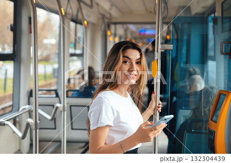 Young Woman Enjoying Her Ride on Public Transport While Using Her Smartphone in a Busy City During the Day 132304439