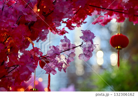Close-up of the artificial peach blossom flower with the Chinese traditional red lantern decor in background. Festive decoration and celebration. Chinese New Year decoration. For background use. 132306162