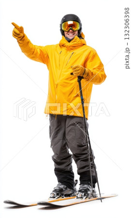 Skiing enthusiast in bright yellow jacket points towards the mountain trail while standing on skis at a snowy ski resort during winter 132306398