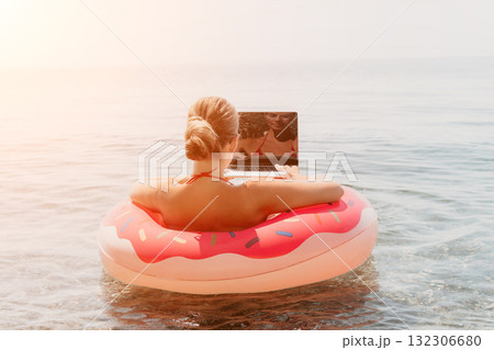 Woman Laptop Beach: Relaxing on a donut float with a laptop in the ocean during a summer day. Woman Laptop Beach: Relaxing on a donut float with a laptop in the ocean during a summer day. 132306680