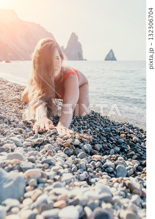 Woman in Red Bikini Kneeling on a Pebble Beach Woman in Red Bikini Kneeling on a Pebble Beach 132306704