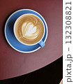 beautifully crafted latte with heart shaped foam art in blue cup, placed on round maroon table, inviting warmth and comfort 132308821