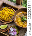 Delicious bowl of curry with noodles, garnished with herbs, served with crispy fried noodles, lime, and fresh vegetables. vibrant and flavorful meal experience 132308844