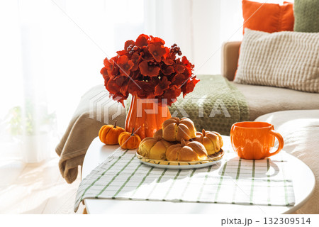 Autumn Living Room with Sofa, Pillows and Pumpkin Cinnamon Buns on Coffee Table Autumn Living Room with Sofa, Pillows and Pumpkin Cinnamon Buns on Coffee Table 132309514