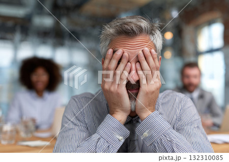 Frustrated businessman covering his face with both hands during a stressful office meeting 132310085