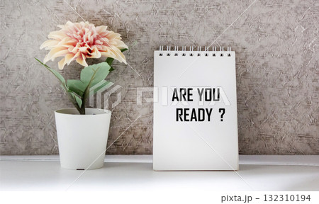 The text You are ready is written on a notebook with a flower on a light background The text You are ready is written on a notebook with a flower on a light background 132310194