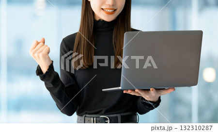 パソコンを見てガッツポーズをする女性・ビジネスウーマン パソコンを見てガッツポーズをする女性・ビジネスウーマン 132310287