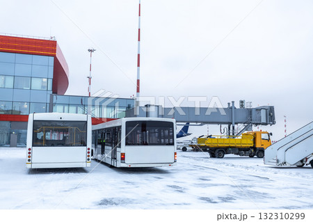 Two airport shuttle buses, a baggage truck and other equipment on the winter airport Two airport shuttle buses, a baggage truck and other equipment on the winter airport 132310299