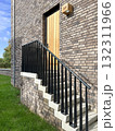 brick house exterior with wooden door, staircase and black metal railing 132311966