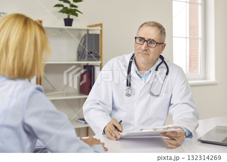 Senior male doctor is listening to his female patient during medical consultation 132314269