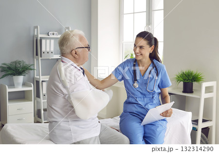 Friendly doctor supporting and helping her senior male patient with a broken arm 132314290