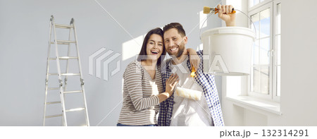 Happy young family couple doing renovations and painting walls in their house together 132314291