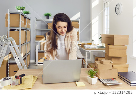 Woman Conducting Parcel Inventory In Post Office Warehouse Using Laptop Woman Conducting Parcel Inventory In Post Office Warehouse Using Laptop 132314293