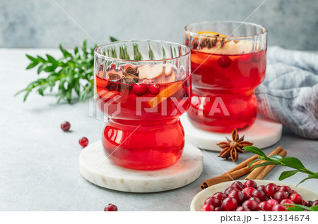 A cranberry drink in a two glasses on a light background with cinnamon, berries close up. A cranberry drink in a two glasses on a light background with cinnamon, berries close up. 132314674