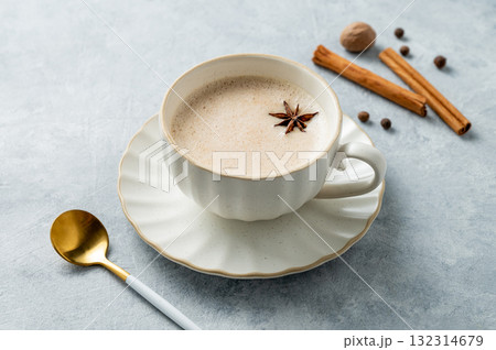 Traditional Indian masala chai tea with milk and spices in a white cup on a light background  132314679