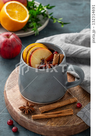 A cup of red mulled wine with spices, orange, apple slices and cranberry on a dark background 132314691