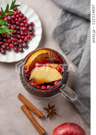 A cup of red mulled wine with spices, orange, apple slices and cranberry on a light background 132314697