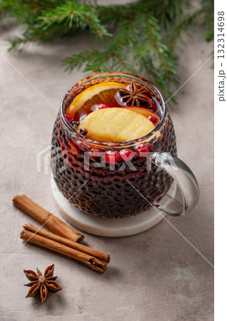 A cup of red mulled wine with spices, orange, apple slices and cranberry on a light background 132314698