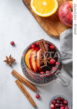 A cup of red mulled wine with spices, orange and apple slices on a light background A cup of red mulled wine with spices, orange and apple slices on a light background 132314702