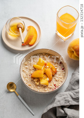 Oatmeal with peaches and nuts  in a bowl on a light background with honey 132314718