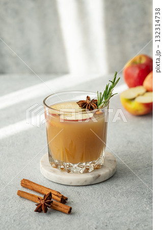 Hot apple cider with cinnamon, anise, and rosemary in glass on a light background with fresh fruits Hot apple cider with cinnamon, anise, and rosemary in glass on a light background with fresh fruits 132314738