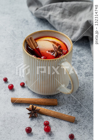 A hot cranberry Christmas drink in a mug on a gray background with cinnamon, berries and napkin 132314748