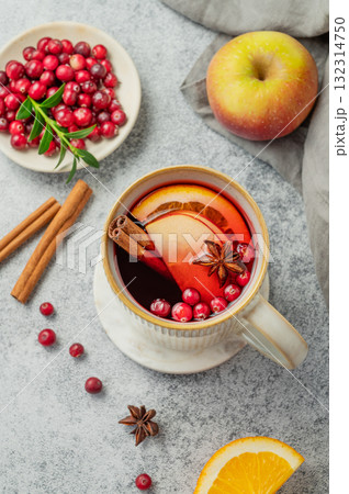 A hot cranberry Christmas drink in a mug on a gray background with cinnamon, berries and fruits. A hot cranberry Christmas drink in a mug on a gray background with cinnamon, berries and fruits. 132314750